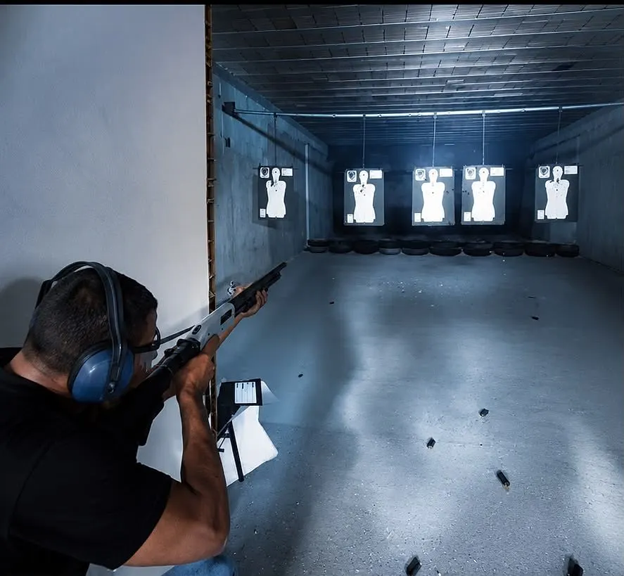 Aluno atira com espingarda calibre 12 em direção aos alvos no estande de tiro
