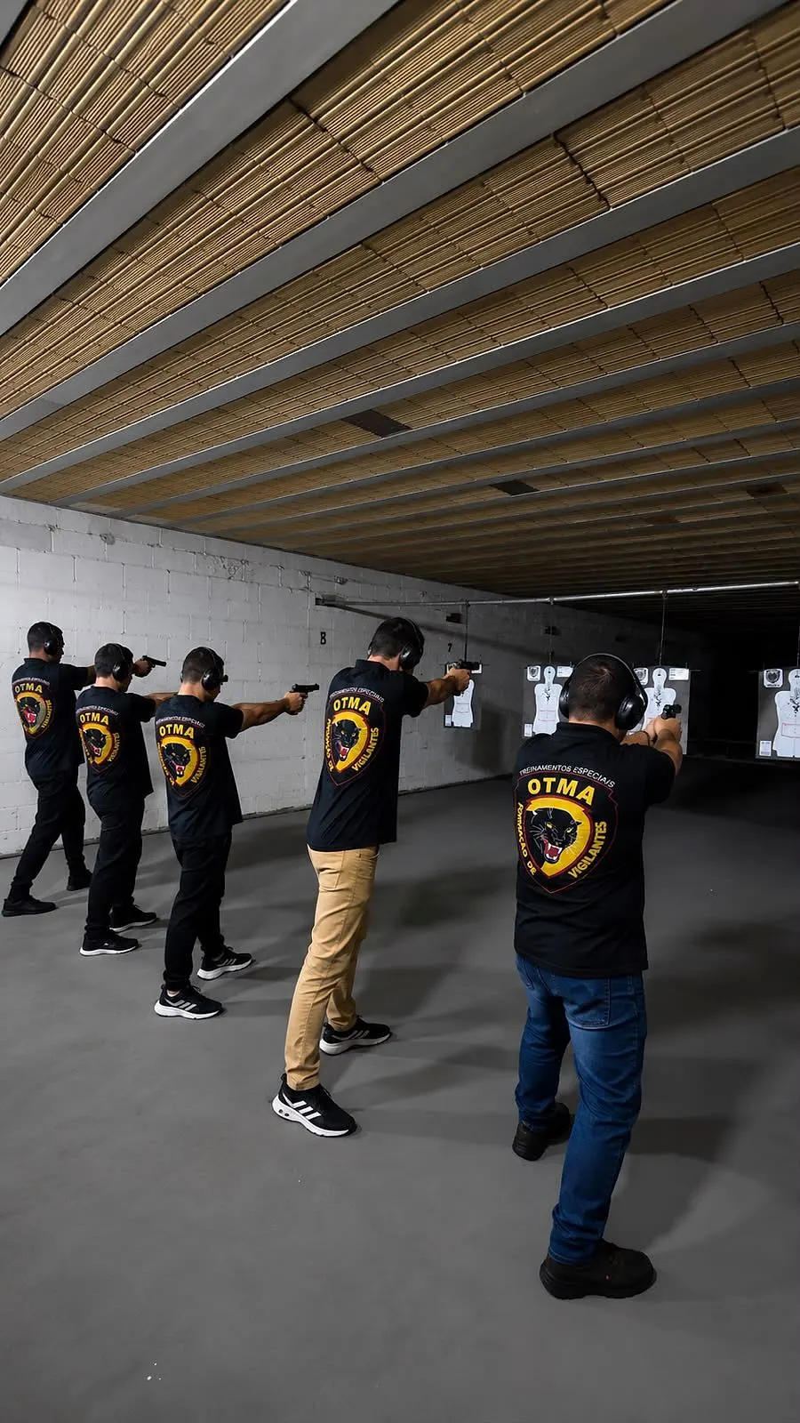 Alunos da OTMA com a camiseta da escola em linha de tiro durante a aula prática de armamento no estande