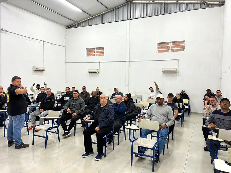 Instrutor conduz aula teórica para uma turma de vigilantes na sala de aula da OTMA
