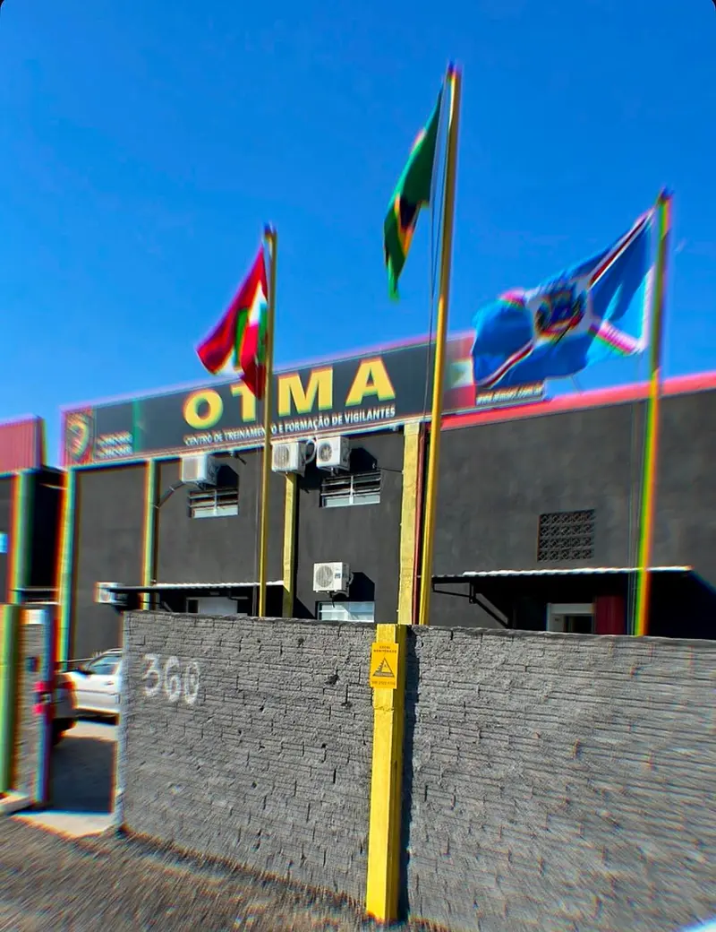Entrada da OTMA no número 360 da Rodovia Olívio Cechinel, em Içara, com bandeiras hasteadas diante do letreiro