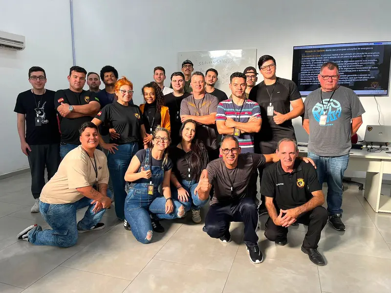 Turma do curso de vigilante reunida com os instrutores na sala de aula da OTMA