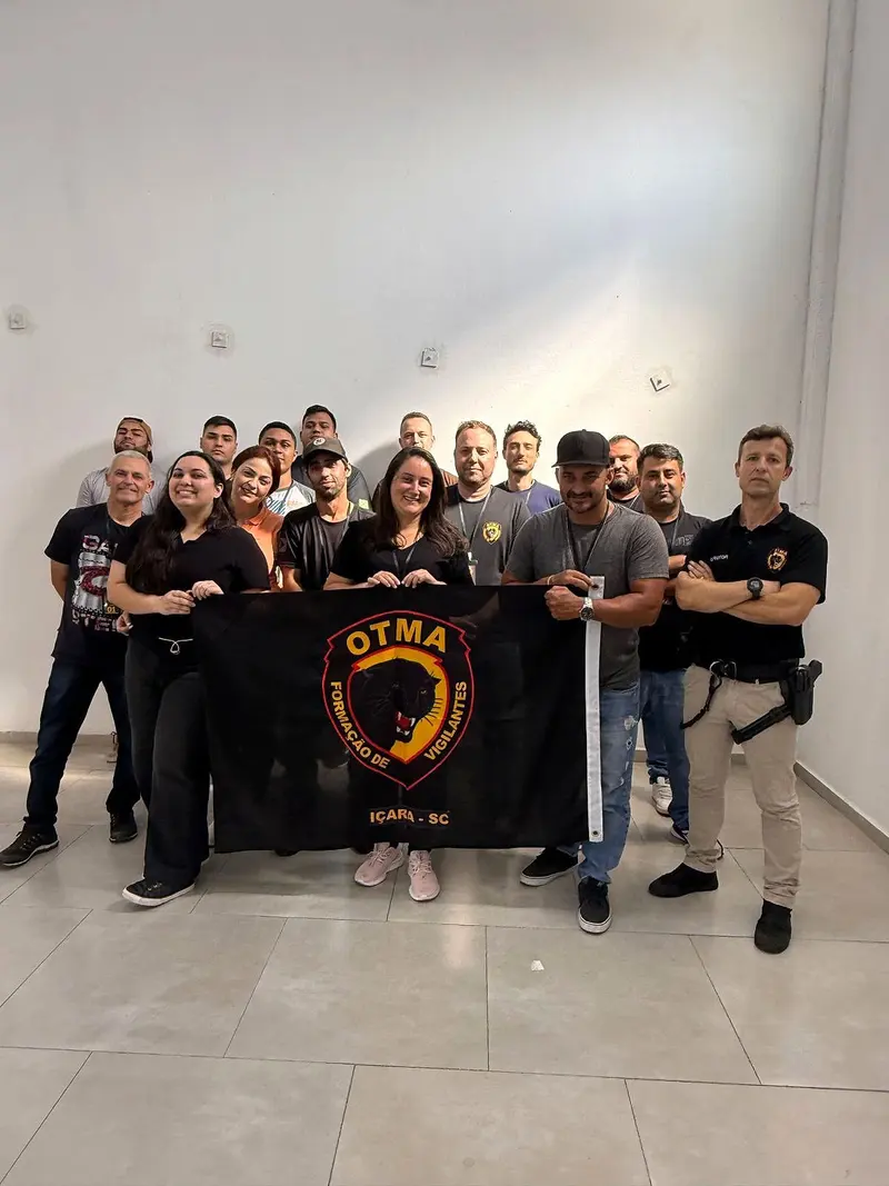 Turma da OTMA posa com a bandeira da escola, que traz a pantera e o nome de Içara (SC)